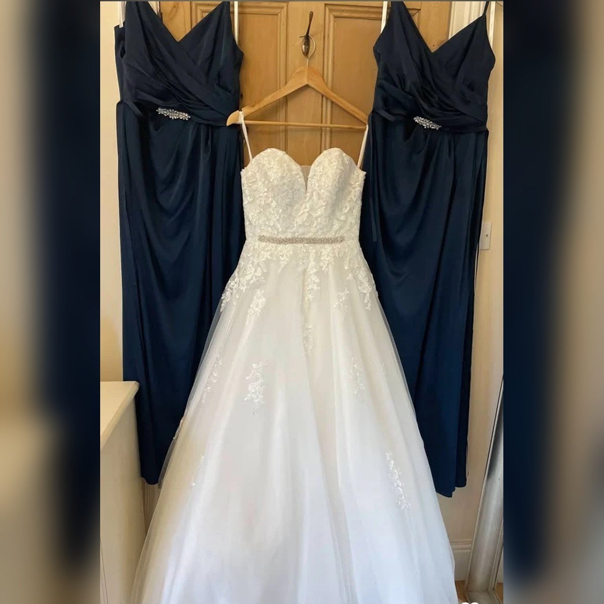 Three emerald satin and lace gowns hanging ready for fitting